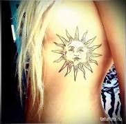 татуировка солнце у красивой блондинки на боку