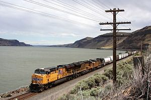 Грузовой поезд, ведомый тепловозом, следует вдоль реки Колумбия (Орегон, США)
