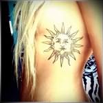 татуировка солнце у красивой блондинки на боку
