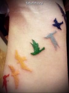 Женская рука в области запястья с татуировками птиц
